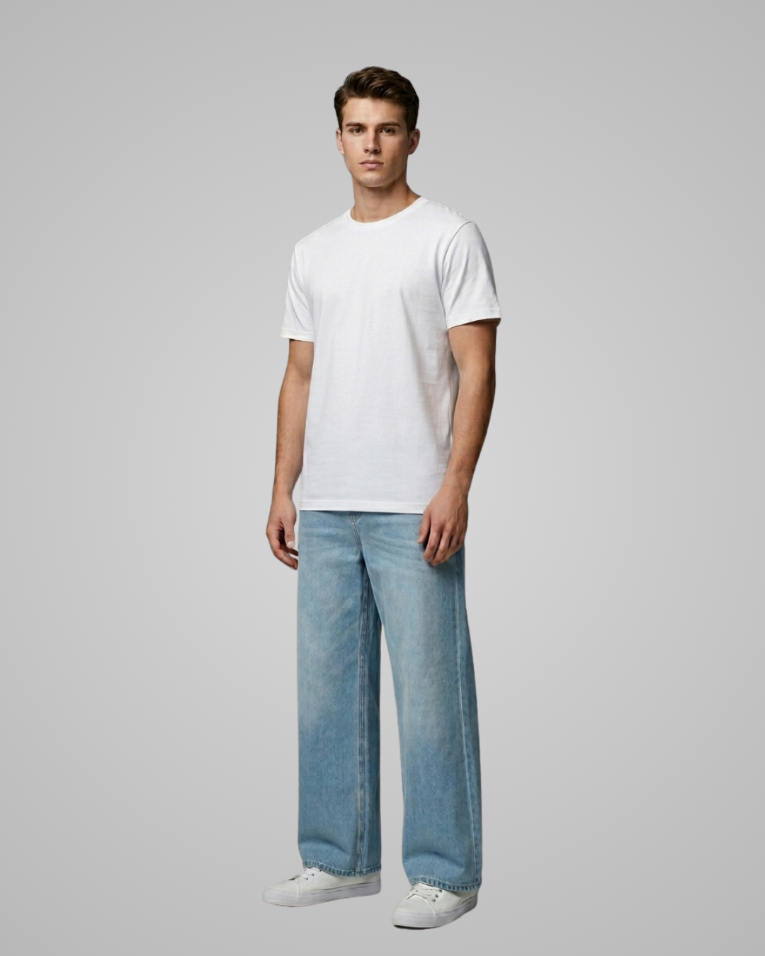 Man wearing a white t-shirt and light blue jeans on a gray background