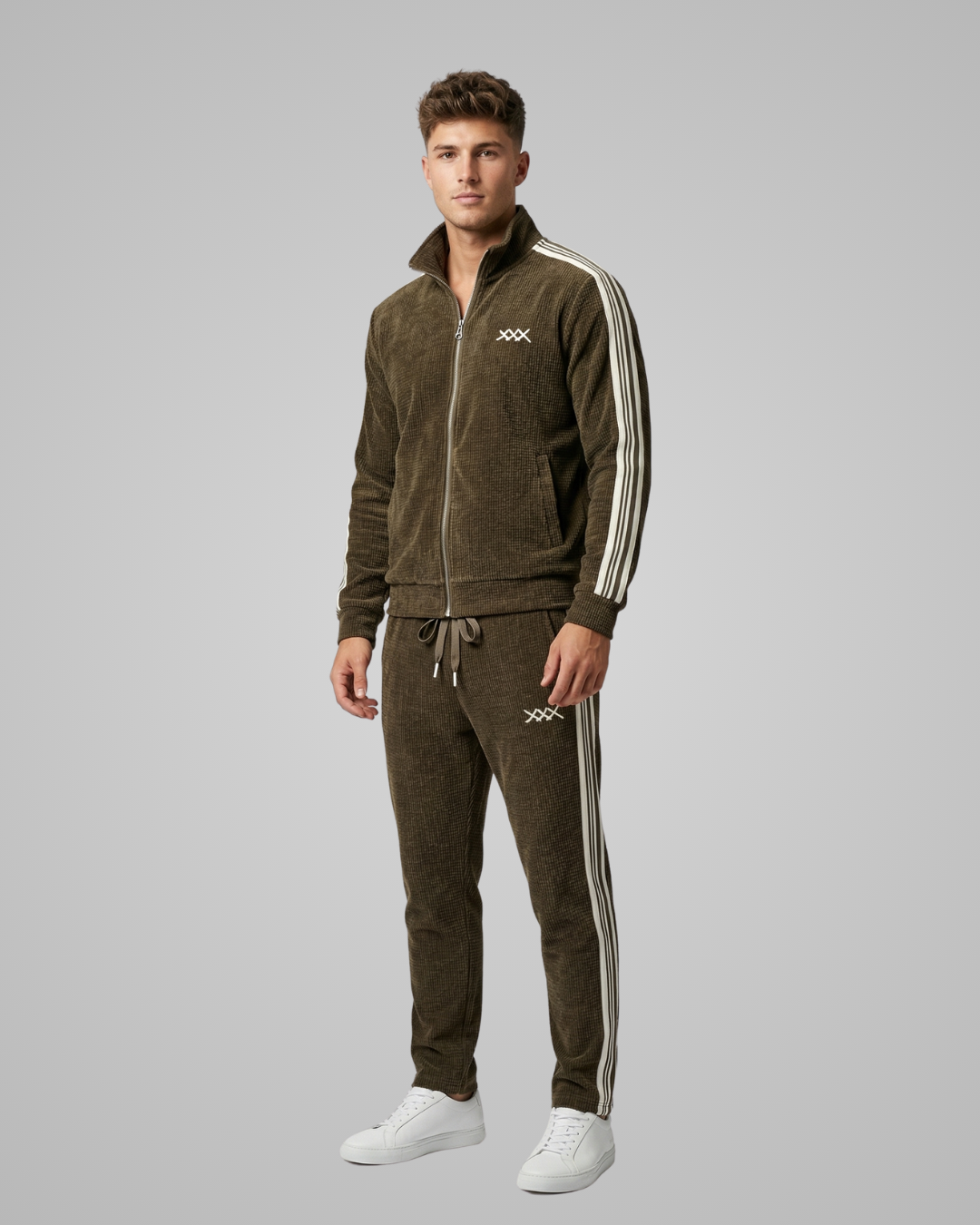 Man wearing a brown tracksuit with white stripes on a gray background
