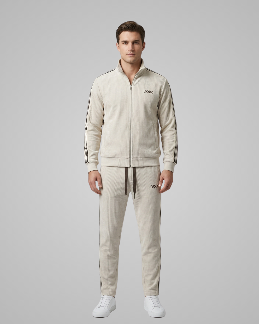 Man wearing a beige tracksuit with a brand logo on a gray background