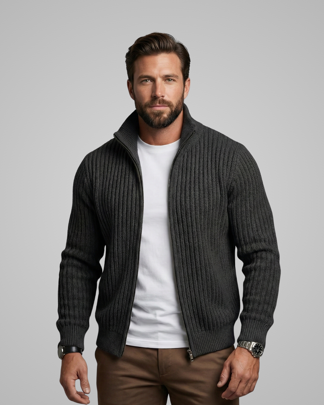 Man wearing a dark gray ribbed sweater over a white shirt with brown pants on a gray background