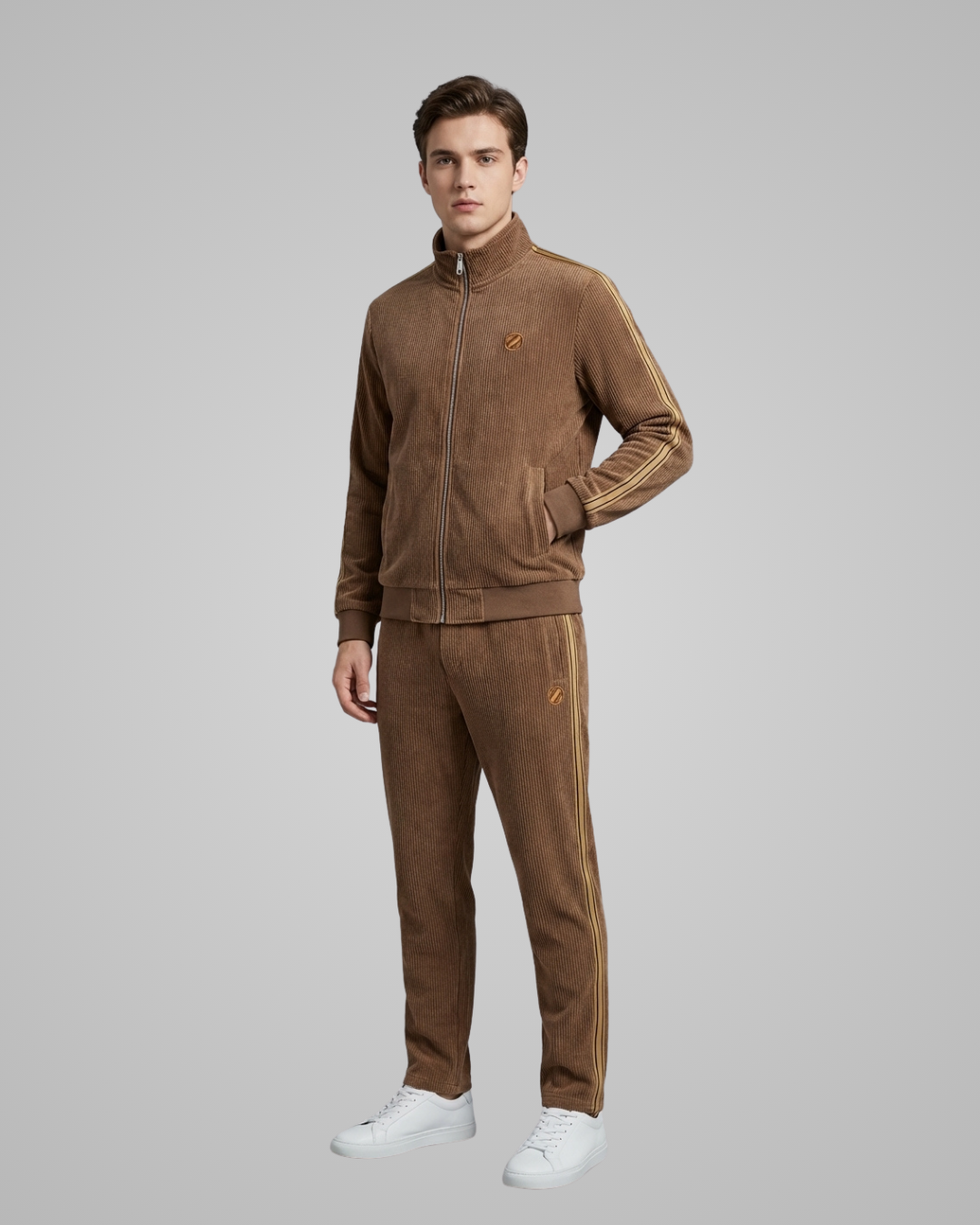 Man wearing a brown tracksuit with white shoes on a gray background