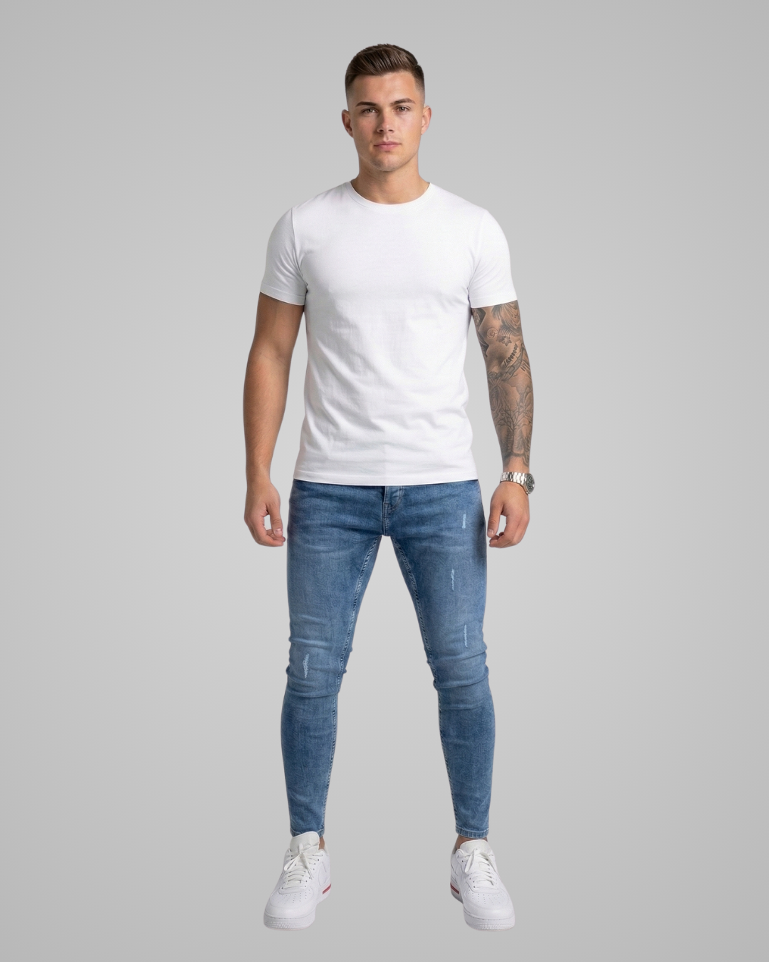 Man wearing a white t-shirt and blue jeans on a gray background