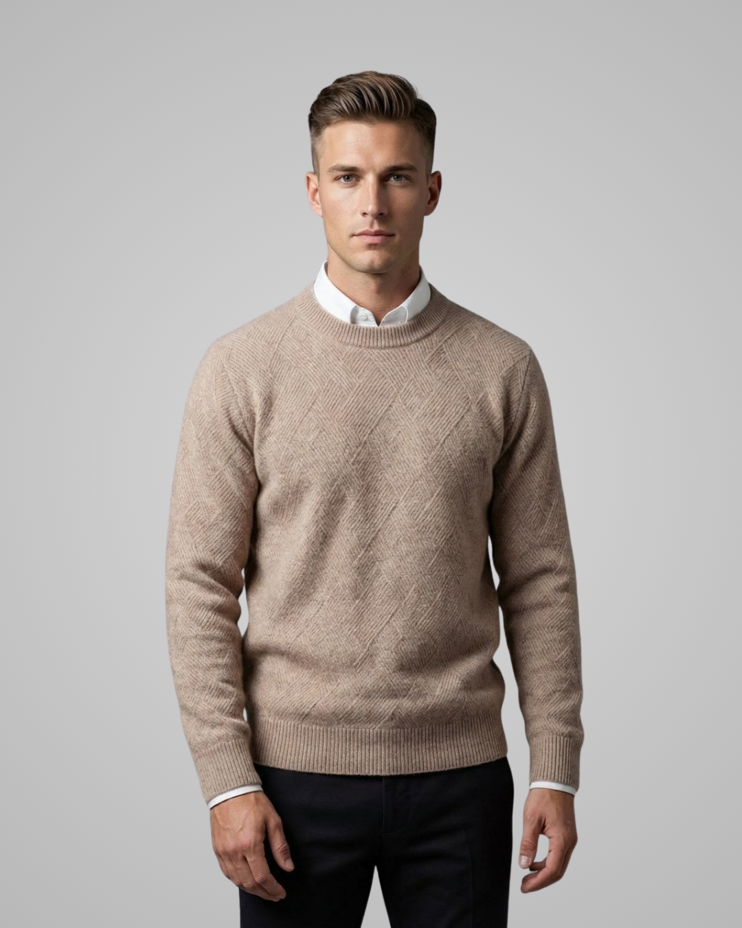 Man wearing a beige sweater over a white shirt on a gray background