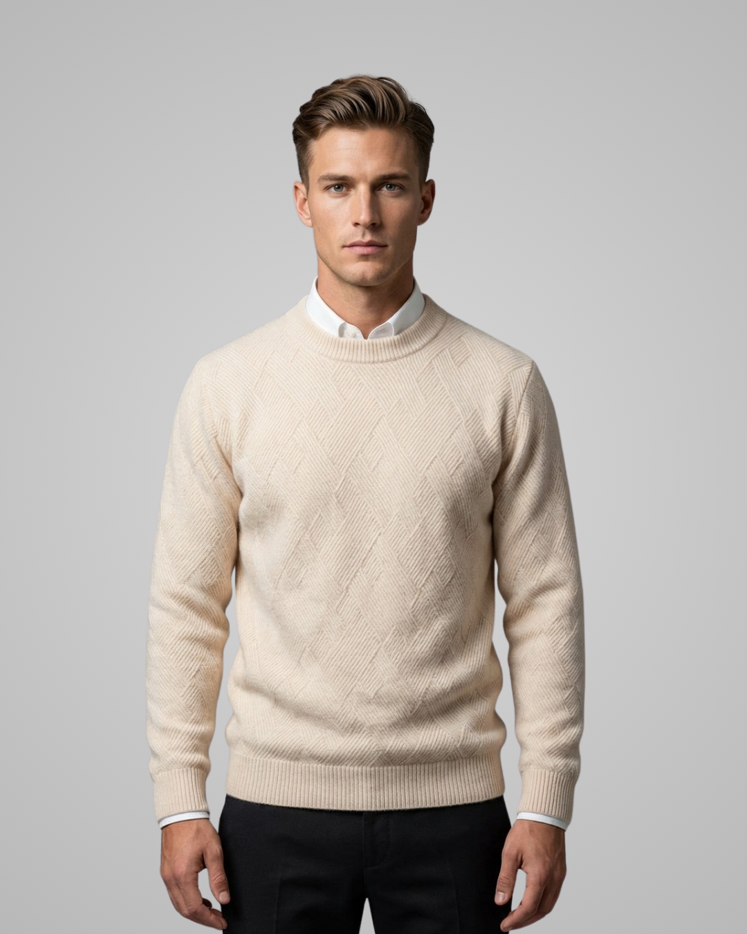 Man wearing a beige sweater over a white shirt on a gray background