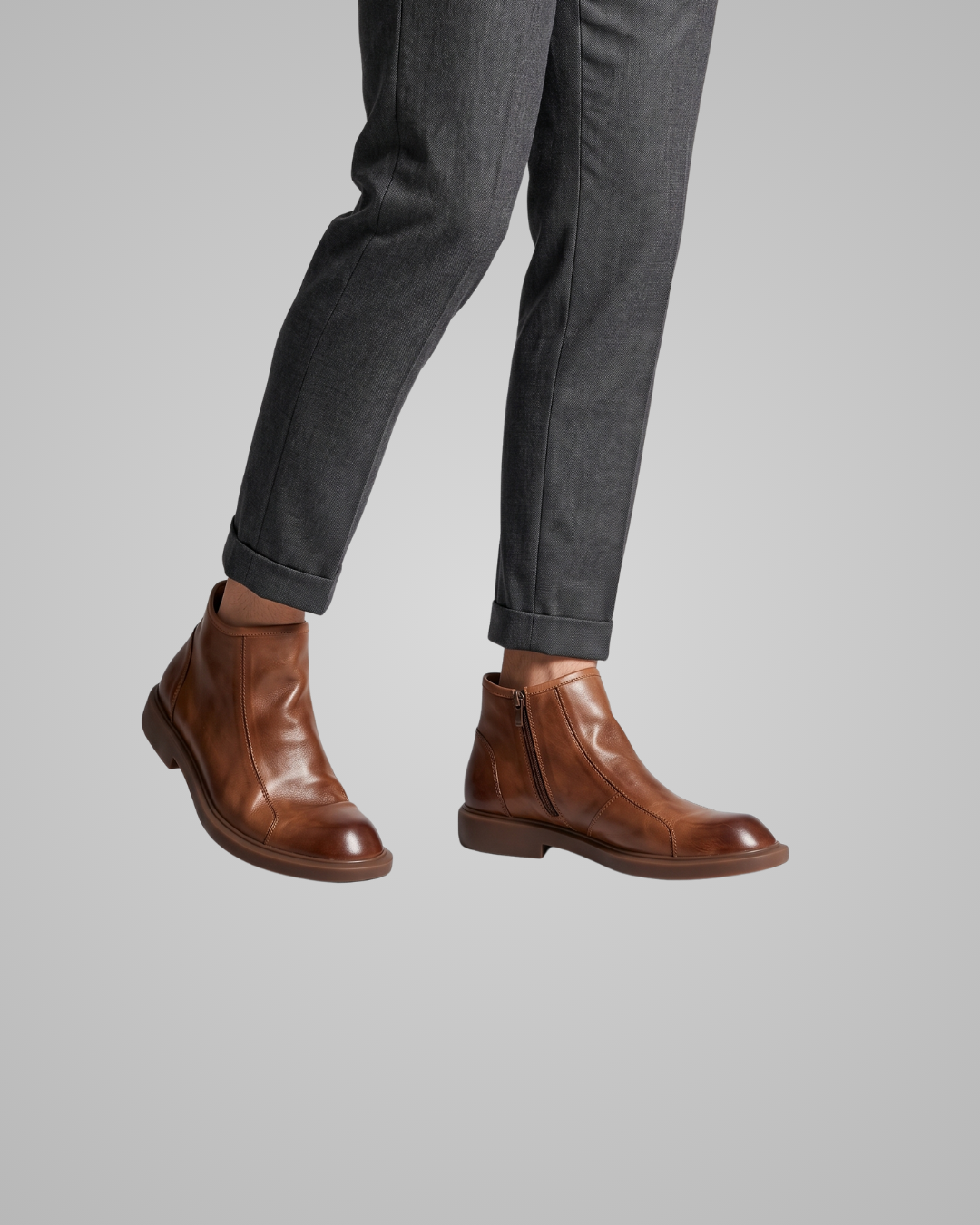 Brown leather boots worn with gray pants on a light gray background