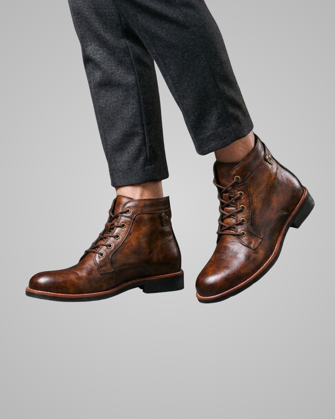 Brown leather boots worn with dark gray pants on a light gray background