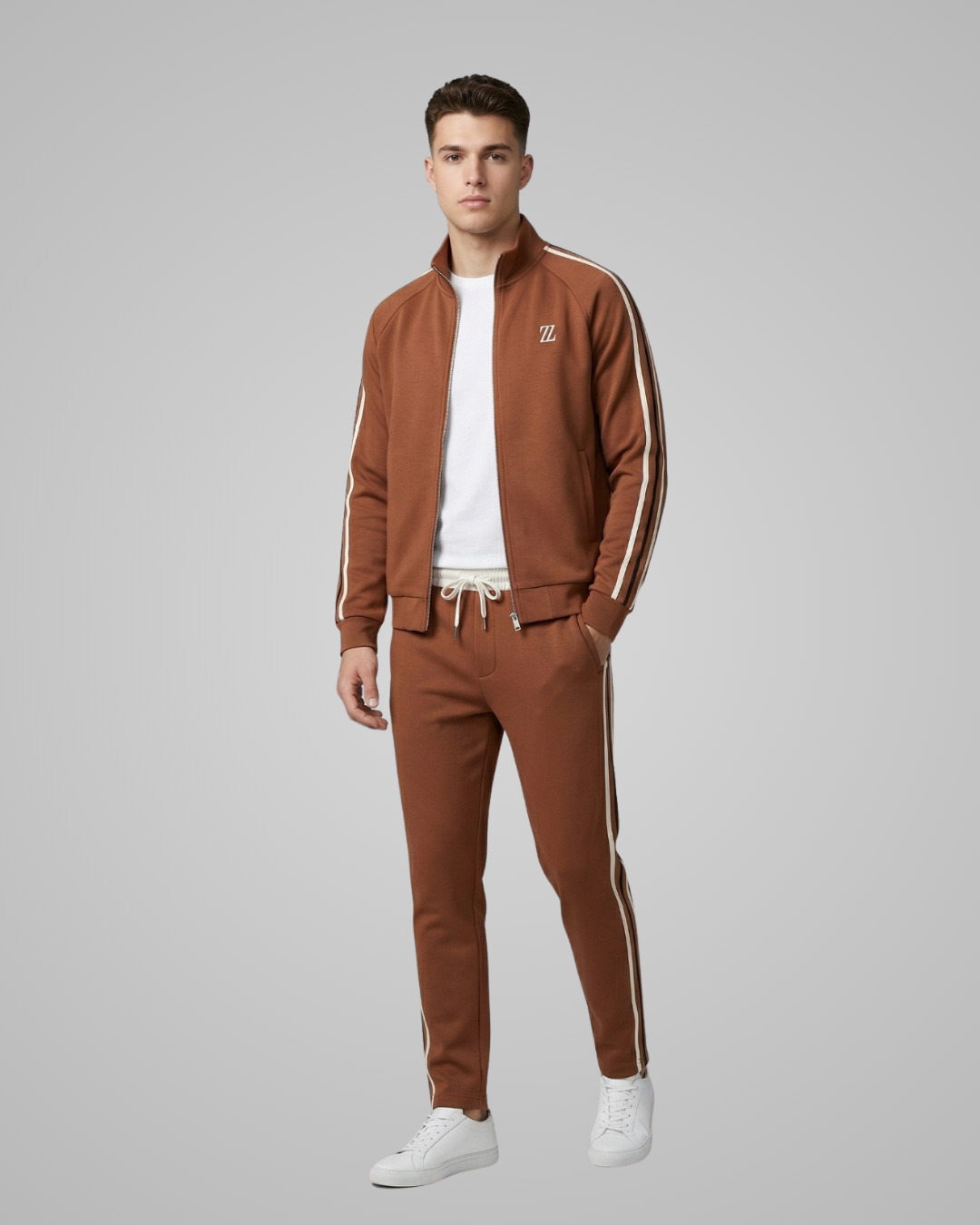 Man wearing a brown tracksuit with white stripes on a gray background