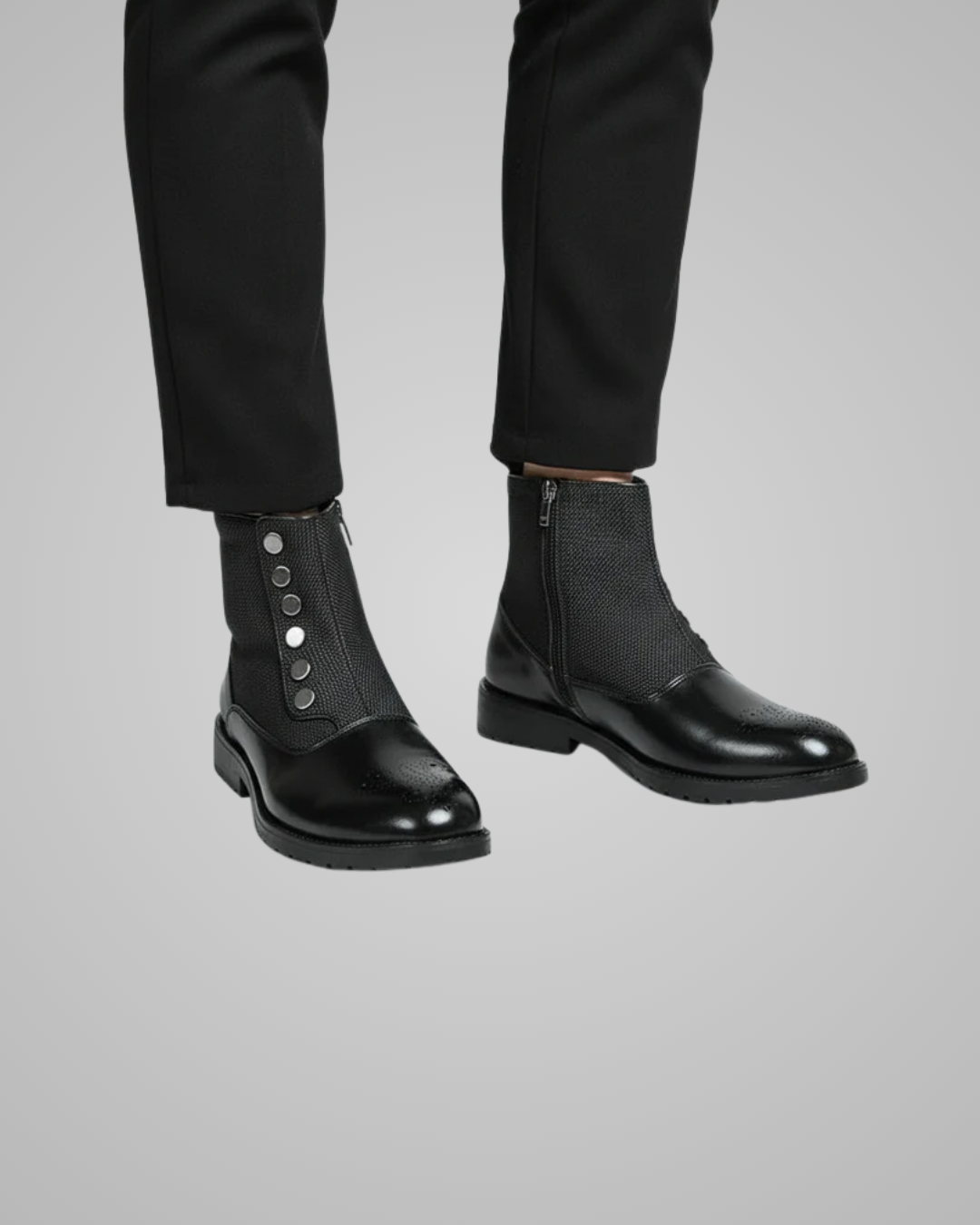 Black leather boots worn with black pants on a gray background
