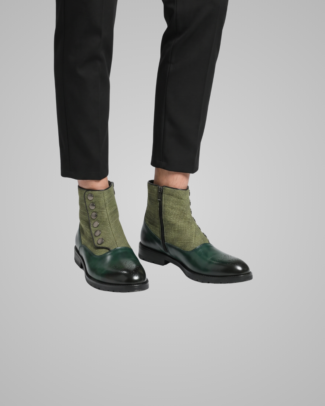 Green and black leather shoes worn with black pants on a gray background