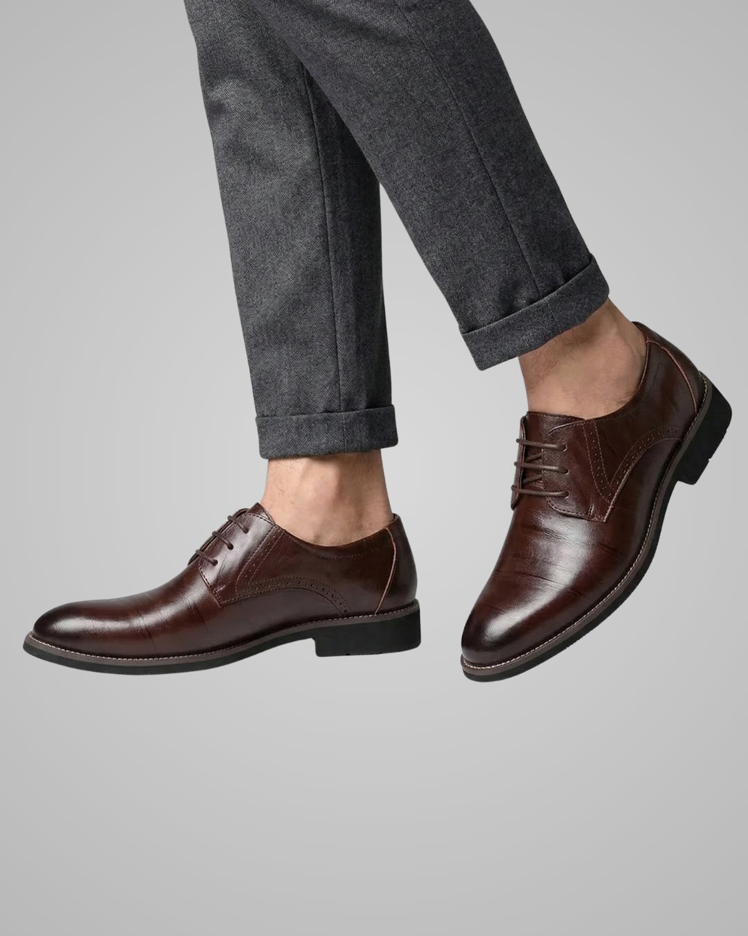 Brown dress shoes worn with gray pants on a light gray background