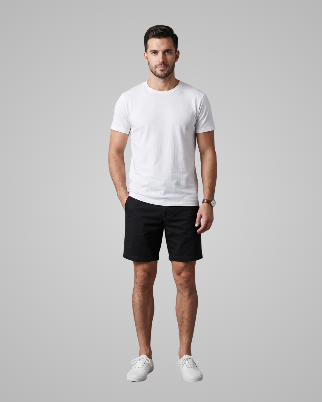 A man modeling a white crew-neck t-shirt and black shorts against a solid gray studio background.