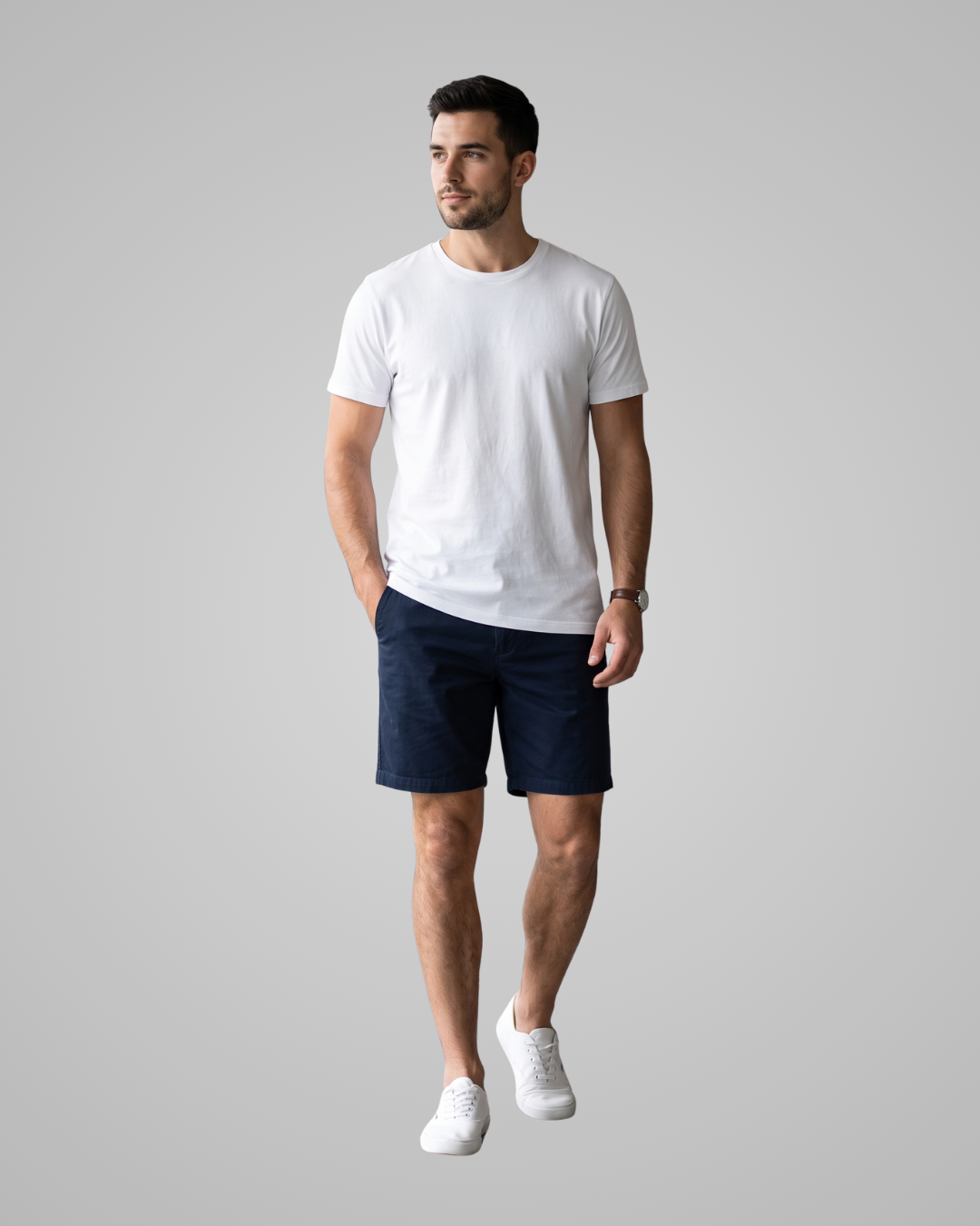 A man modeling a white crew-neck t-shirt and dark navy blue shorts against a solid gray studio background.