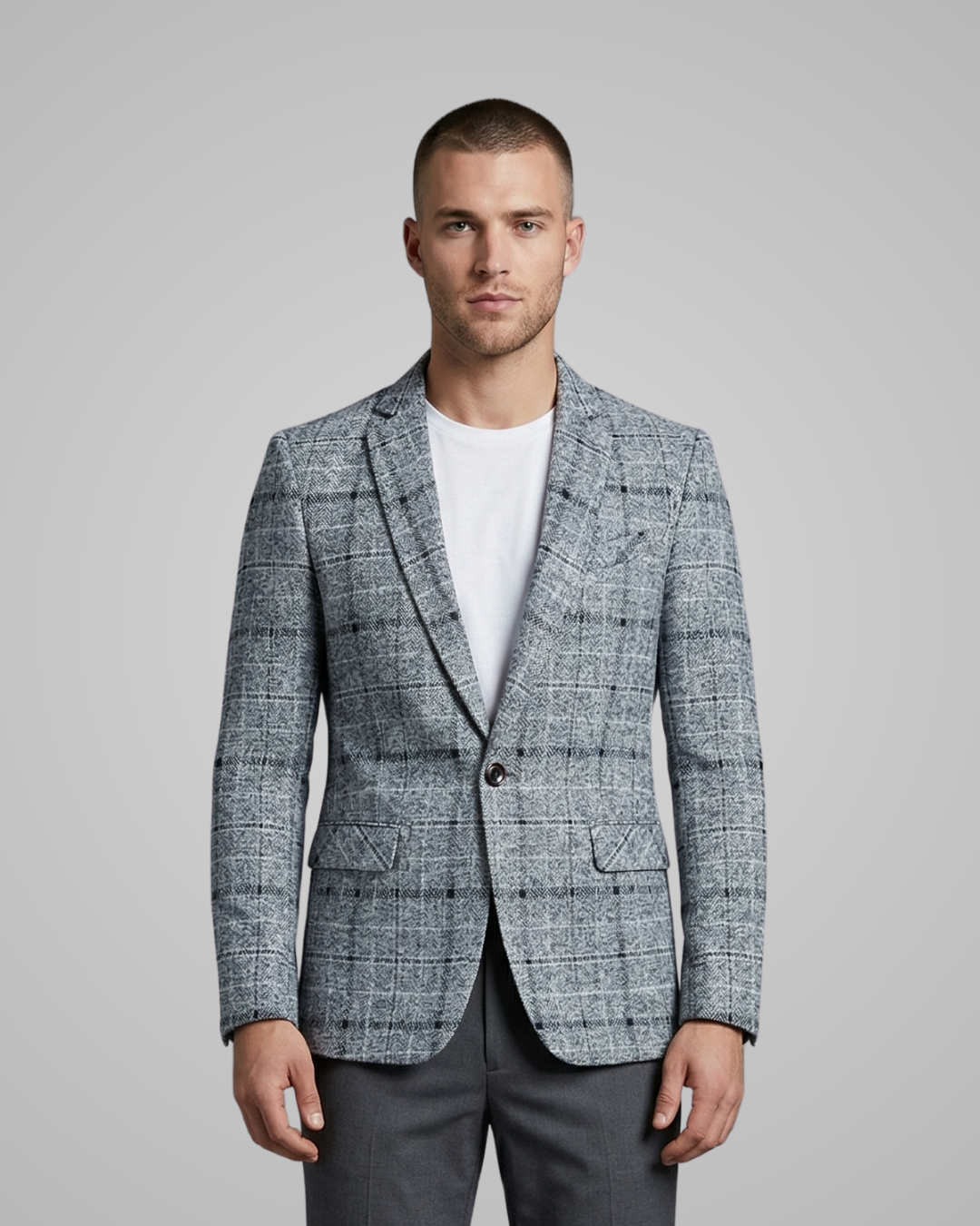 Man wearing a gray checkered blazer over a white shirt on a gray background