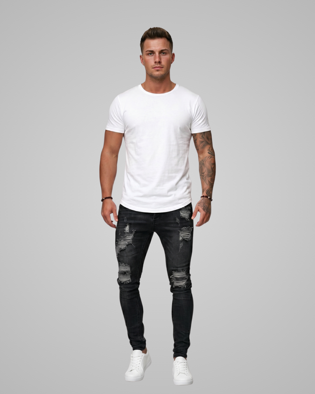 Man wearing a white t-shirt and black distressed jeans on a gray background