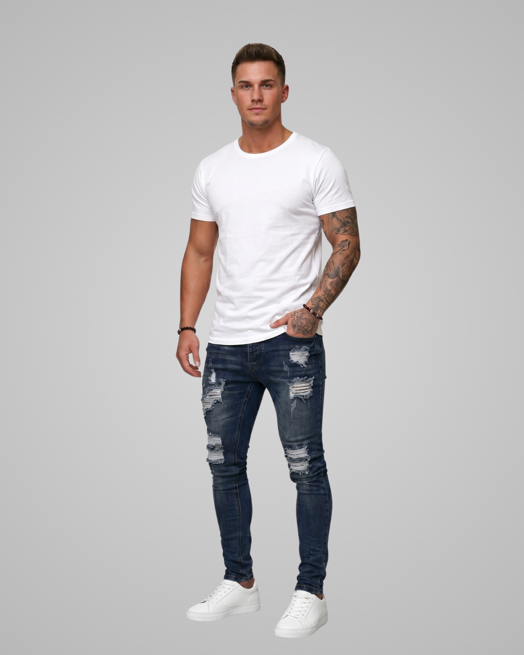 Man wearing a white t-shirt and distressed jeans on a gray background