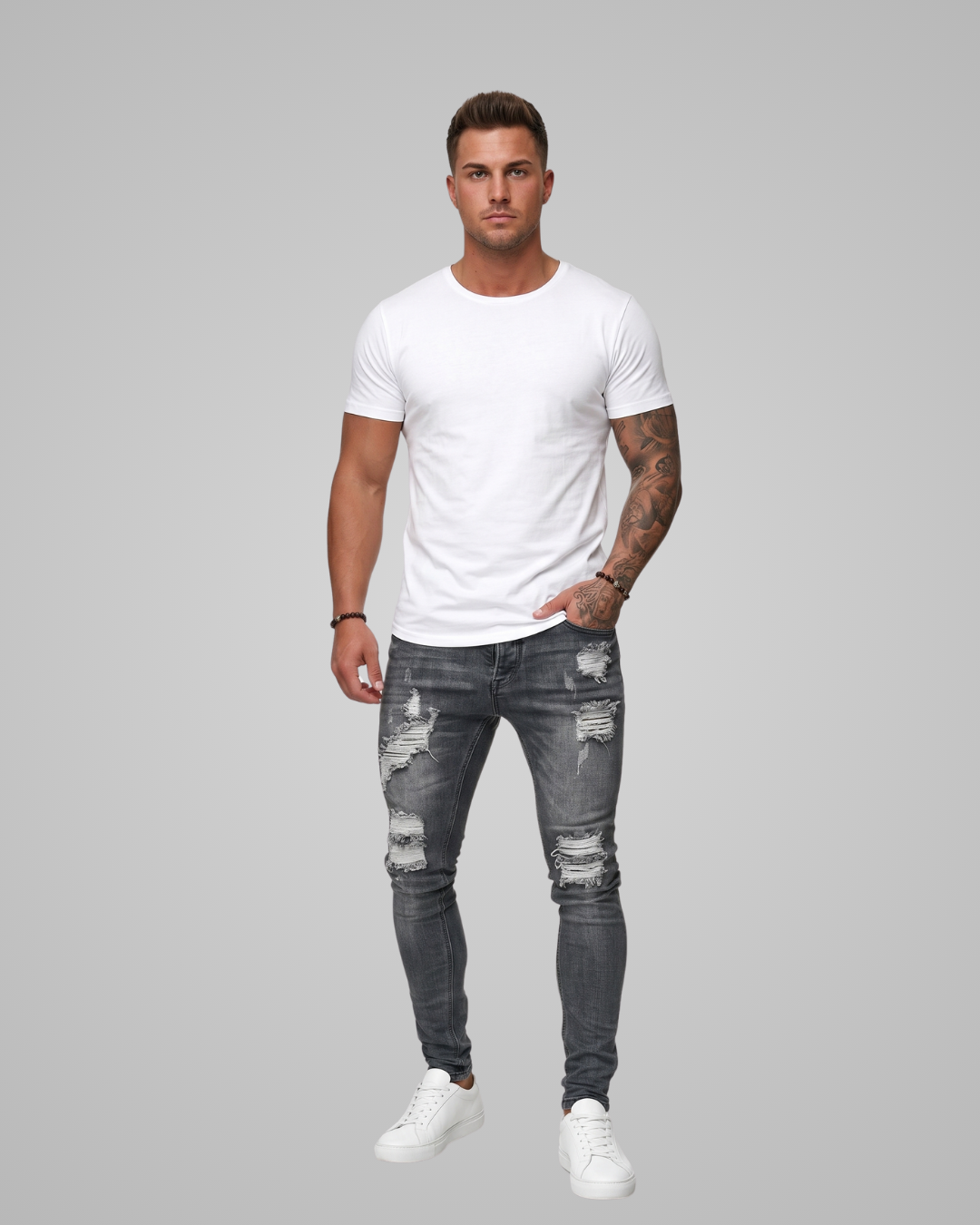 Man wearing a white t-shirt and gray distressed jeans on a gray background