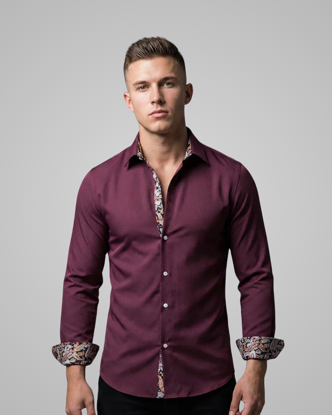 Man wearing a maroon shirt with patterned cuffs against a gray background