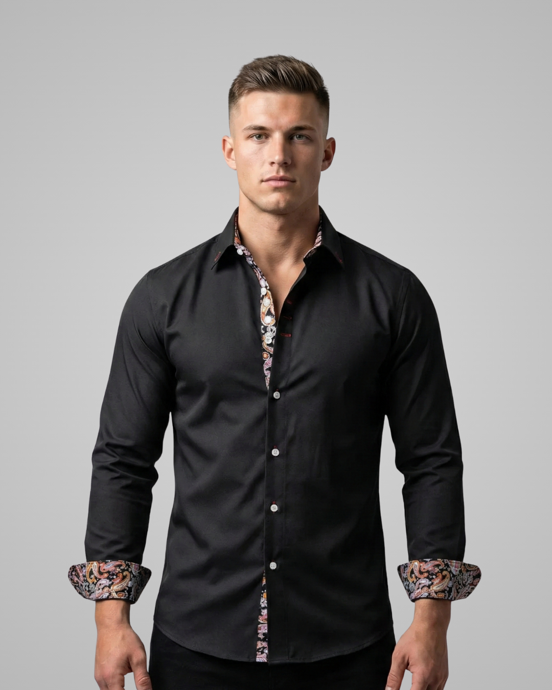 Man wearing a black dress shirt with patterned cuffs against a gray background