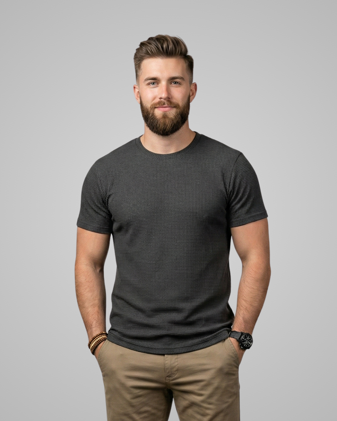 Man wearing a dark gray t-shirt and beige pants against a light gray background