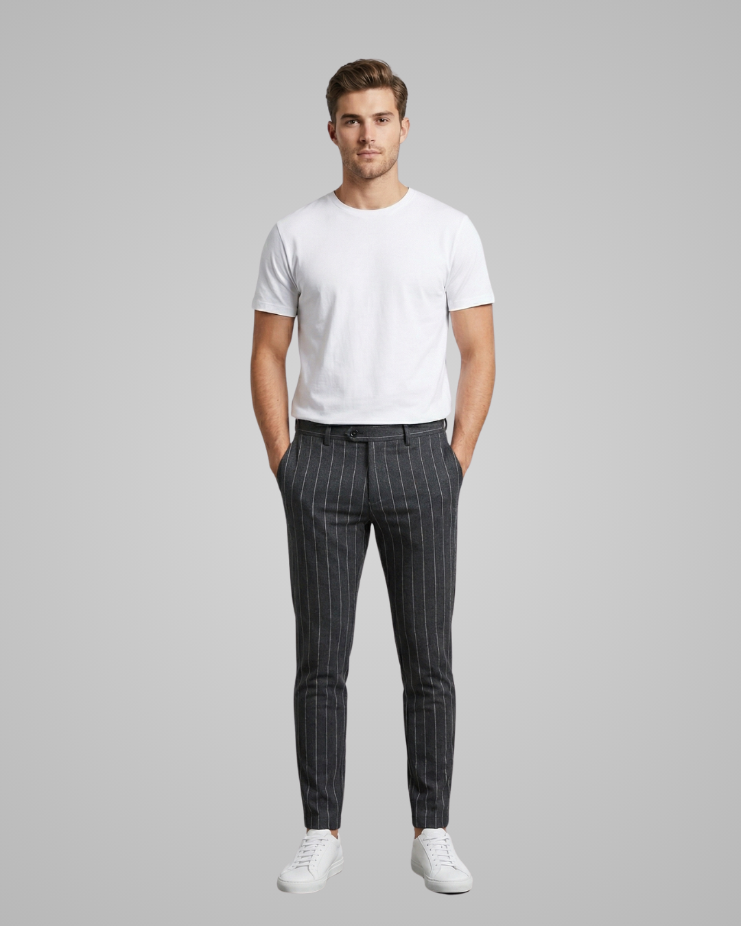Man wearing a white t-shirt and black pinstripe pants on a gray background