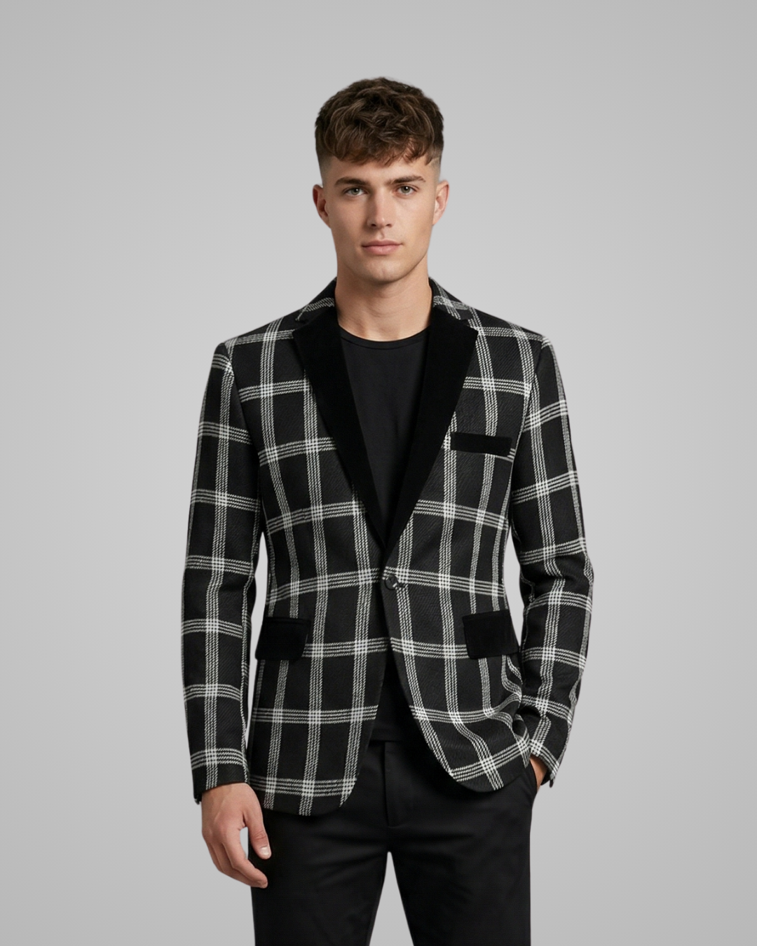 Man wearing a black and gray checkered blazer over a black shirt on a gray background