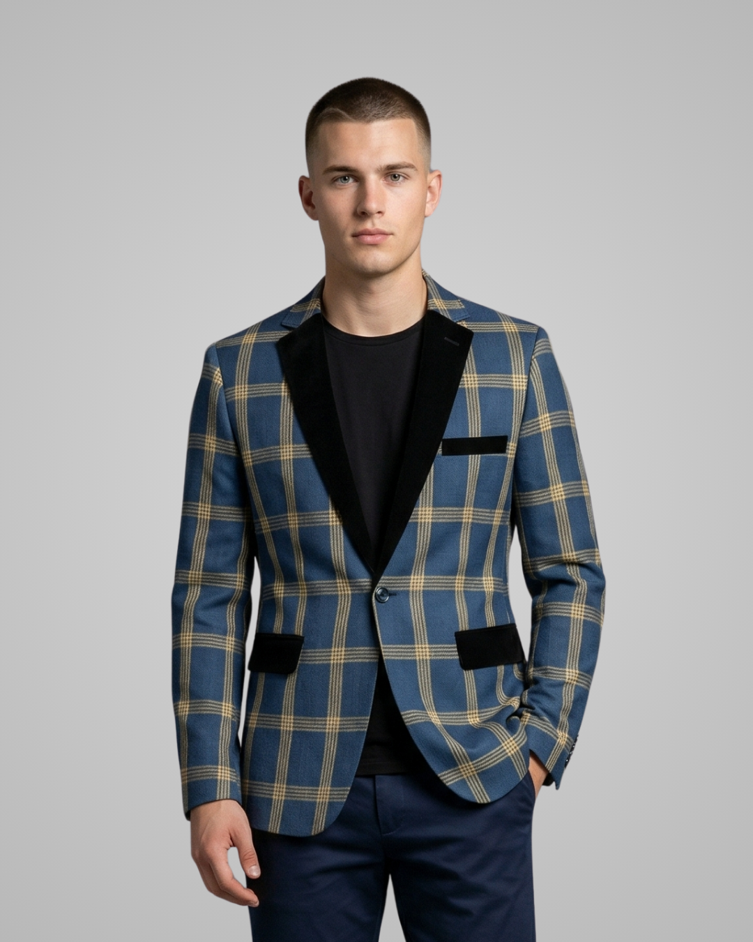 Man wearing a blue checkered blazer over a black shirt on a gray background