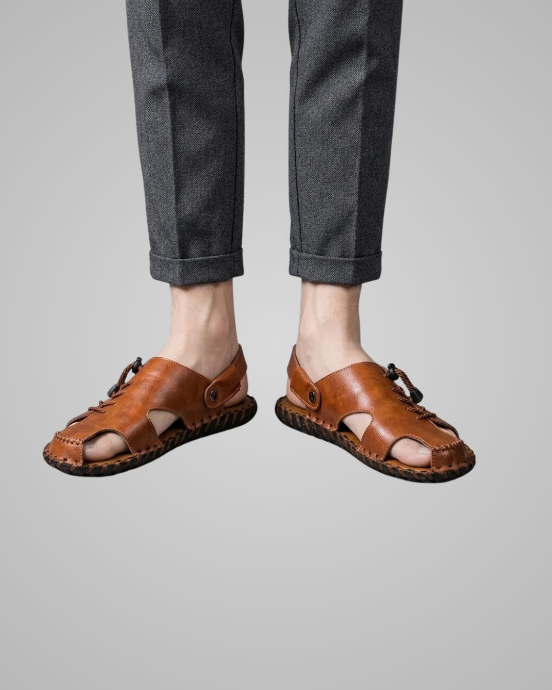 Brown sandals worn with gray pants on a plain background