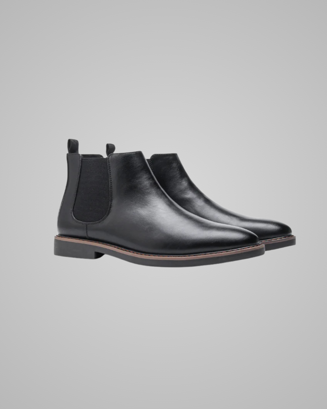 Pair of black leather Chelsea boots on a gray background