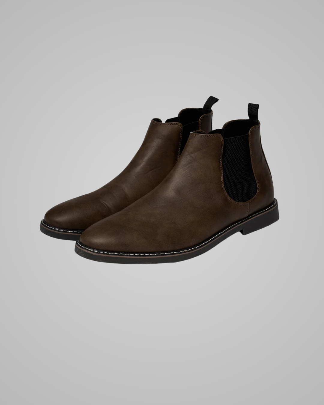 Pair of brown leather Chelsea boots on a gray background