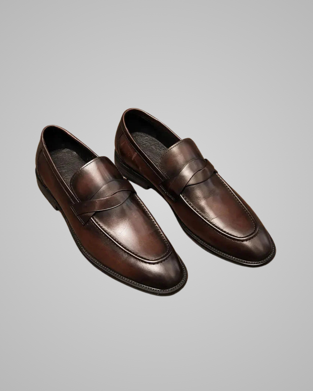 A pair of dark brown leather penny loafers with a polished finish, displayed on a neutral gray background.