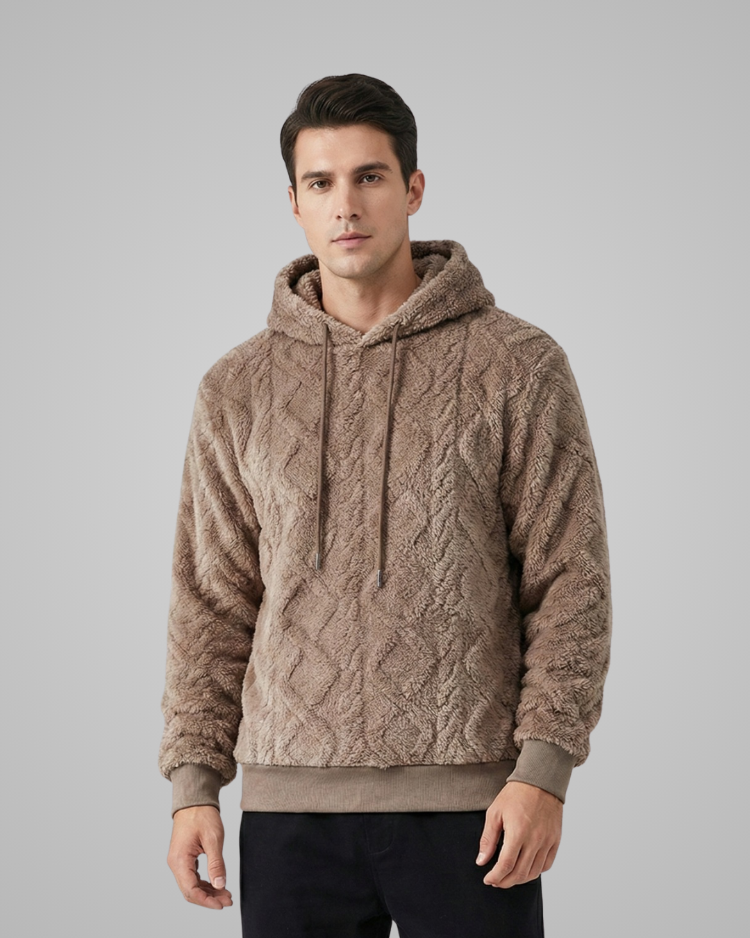 Man wearing a beige cable knit hoodie against a gray background