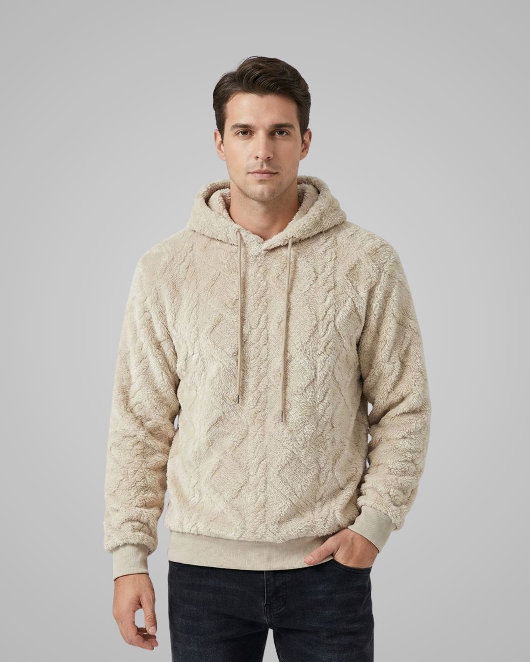Man wearing a beige cable knit hoodie against a gray background