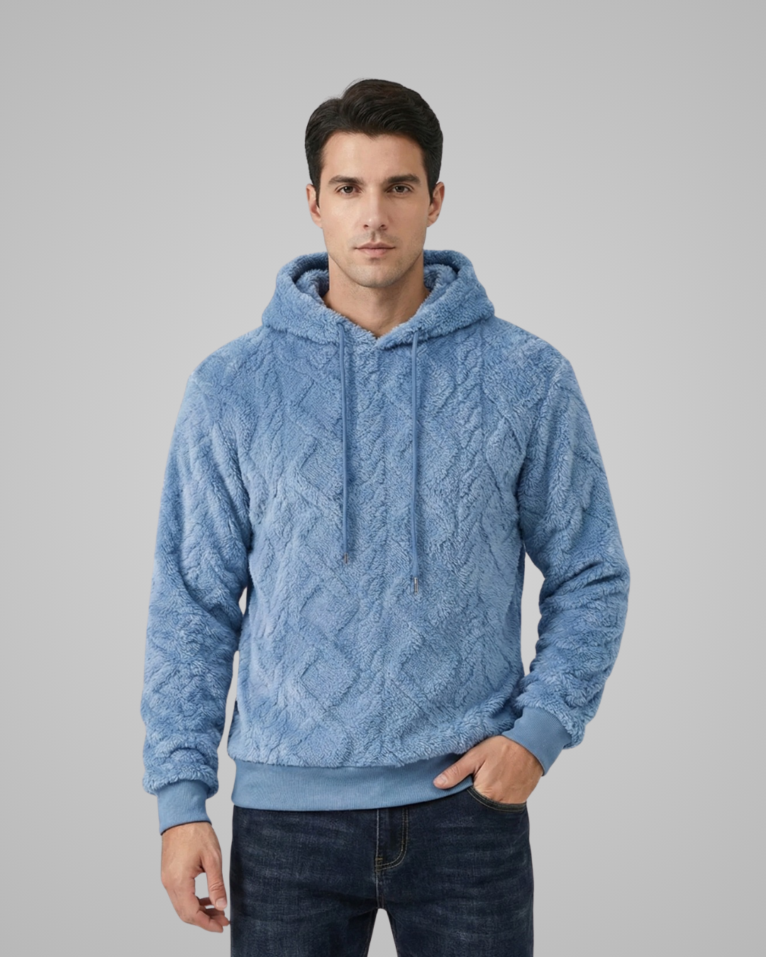 Man wearing a blue cable knit hoodie against a gray background