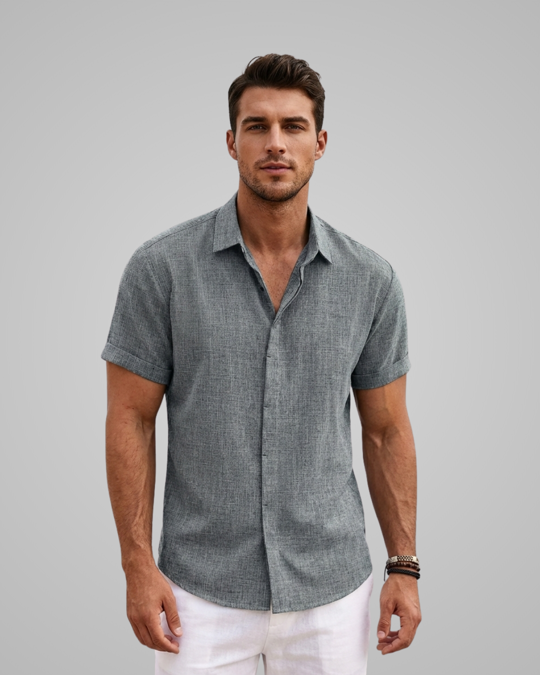 Man wearing a gray short-sleeve shirt and white pants against a gray background