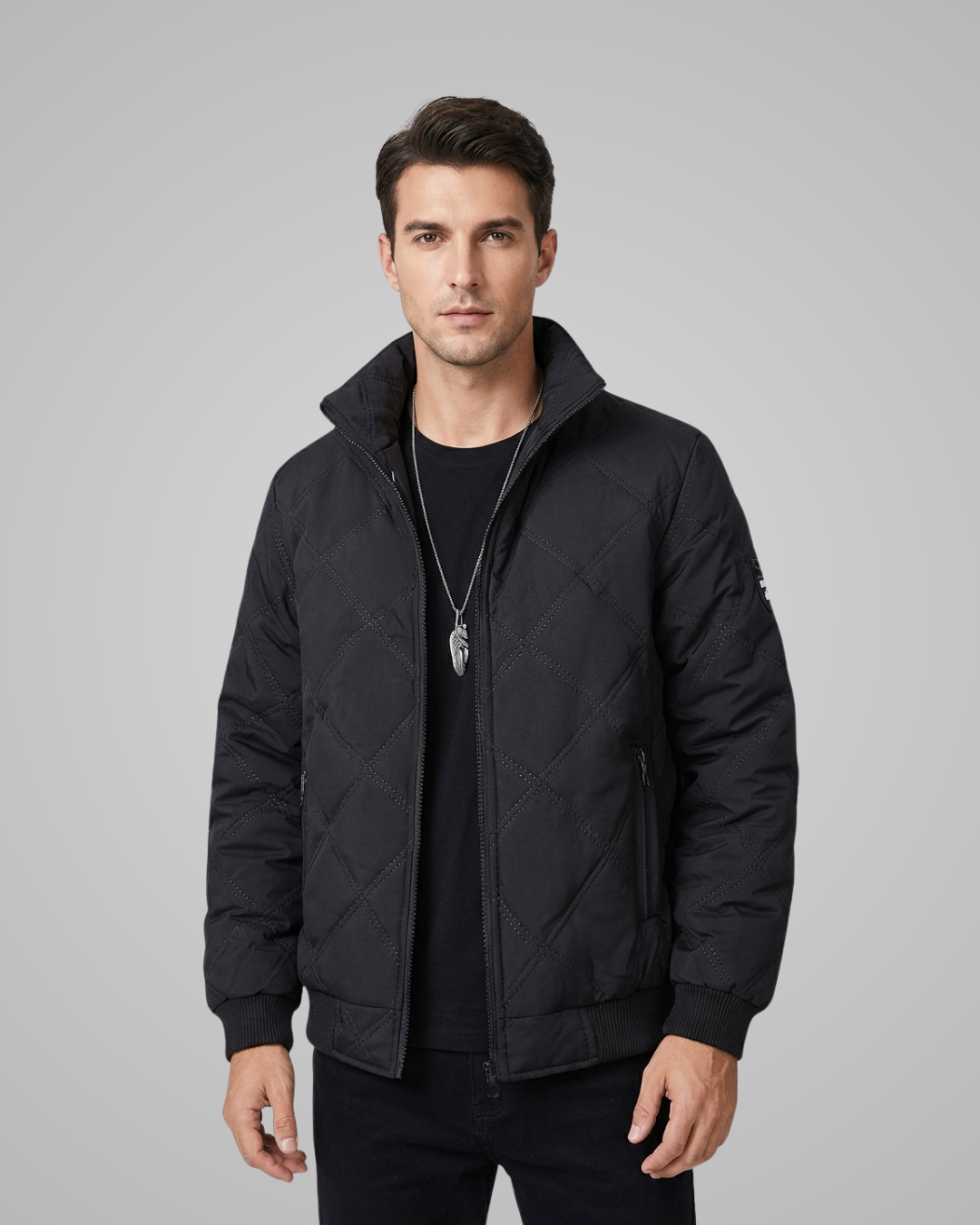 Man wearing a black quilted jacket on a gray background