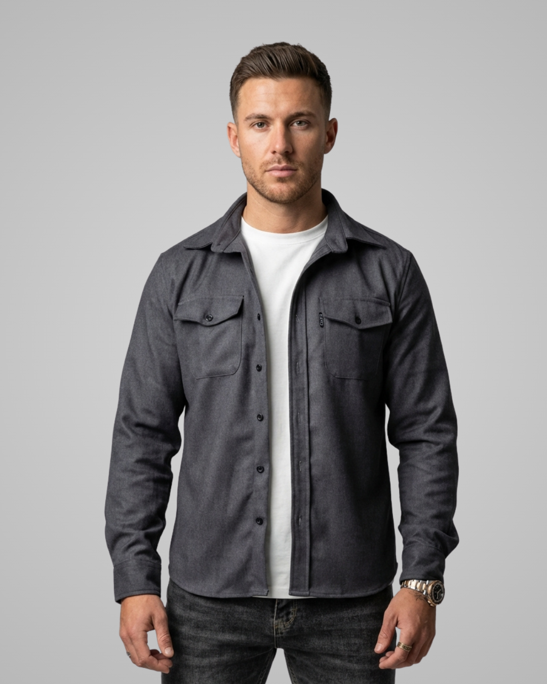 Man wearing a gray jacket over a white shirt on a gray background