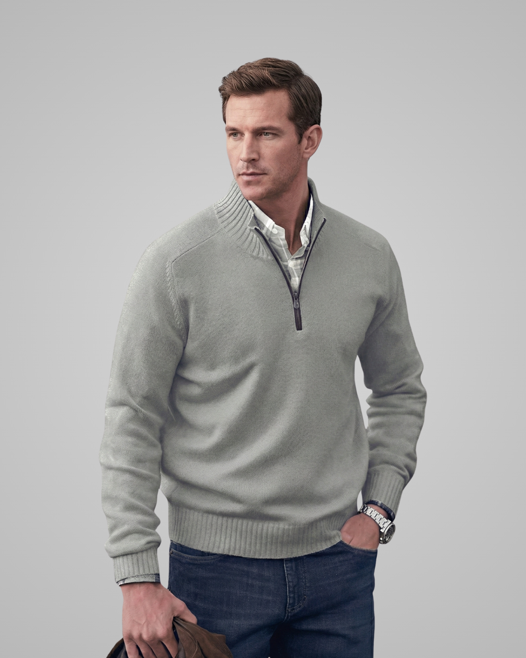 Man wearing a light gray sweater over a collared shirt with a gray background