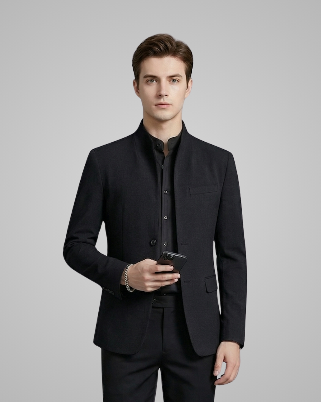 Man wearing a black suit holding a smartphone against a gray background