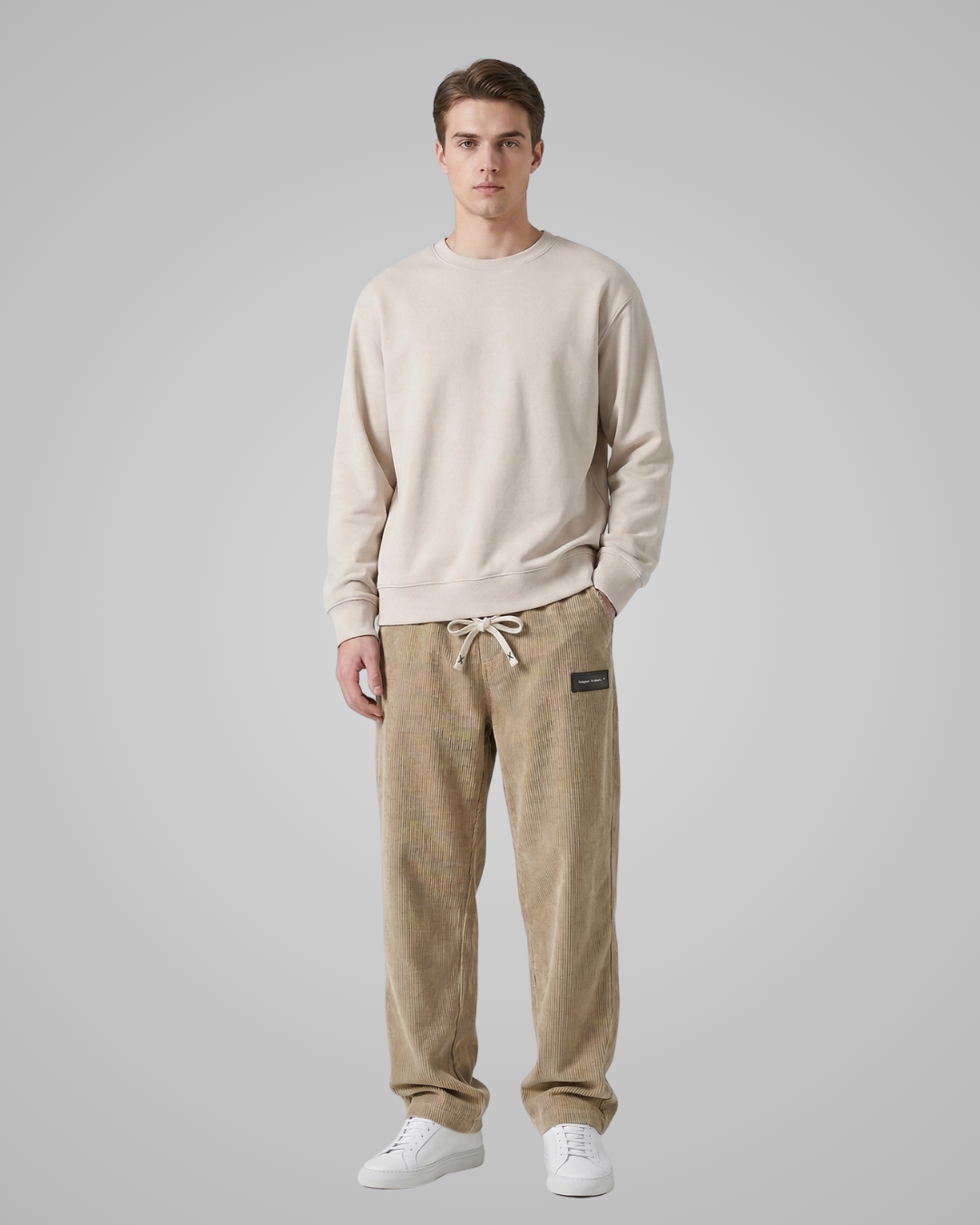 Man wearing a beige sweater and tan pants on a gray background