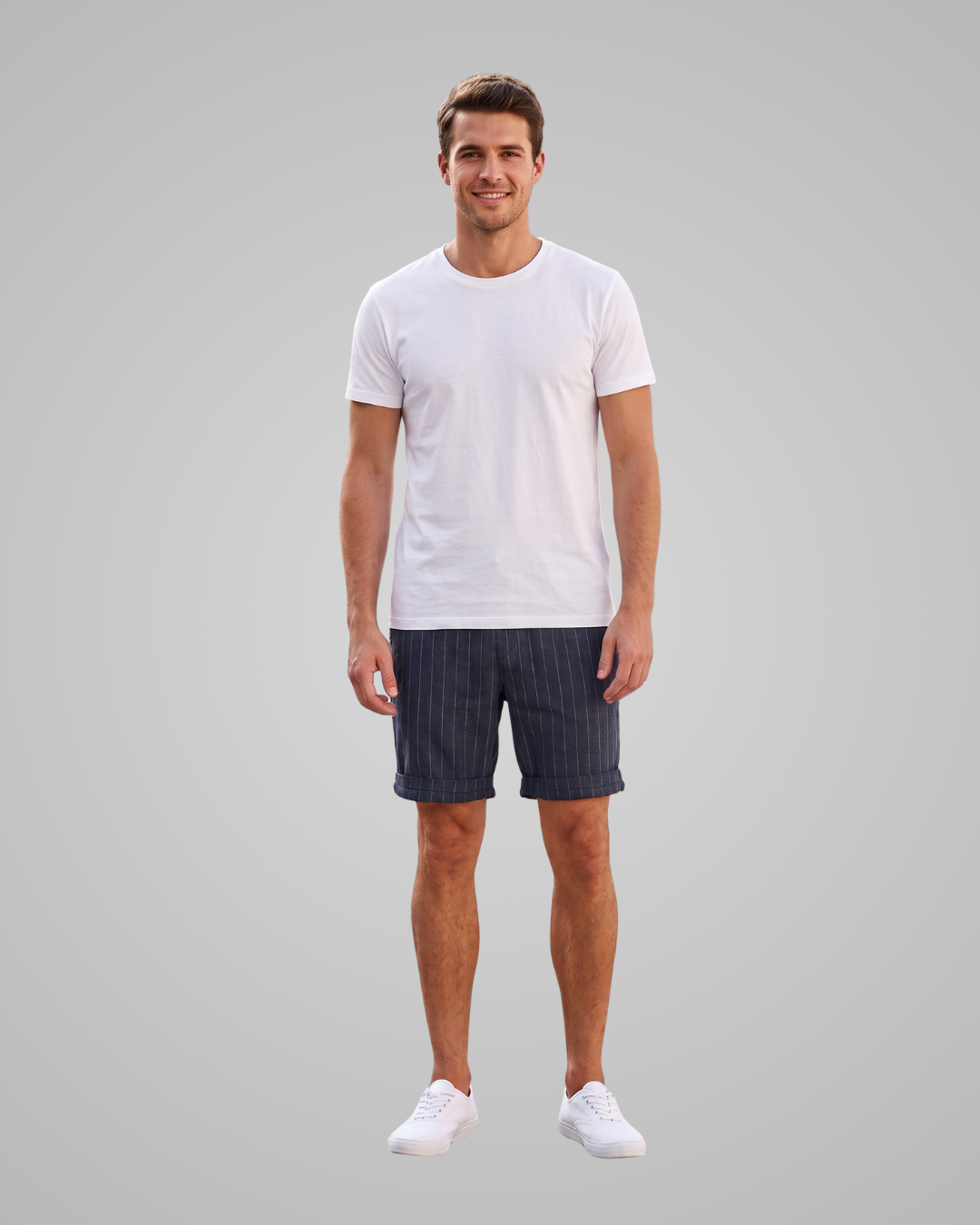 A man modeling a white short-sleeve crewneck t-shirt and dark navy pinstriped shorts against a solid gray background.