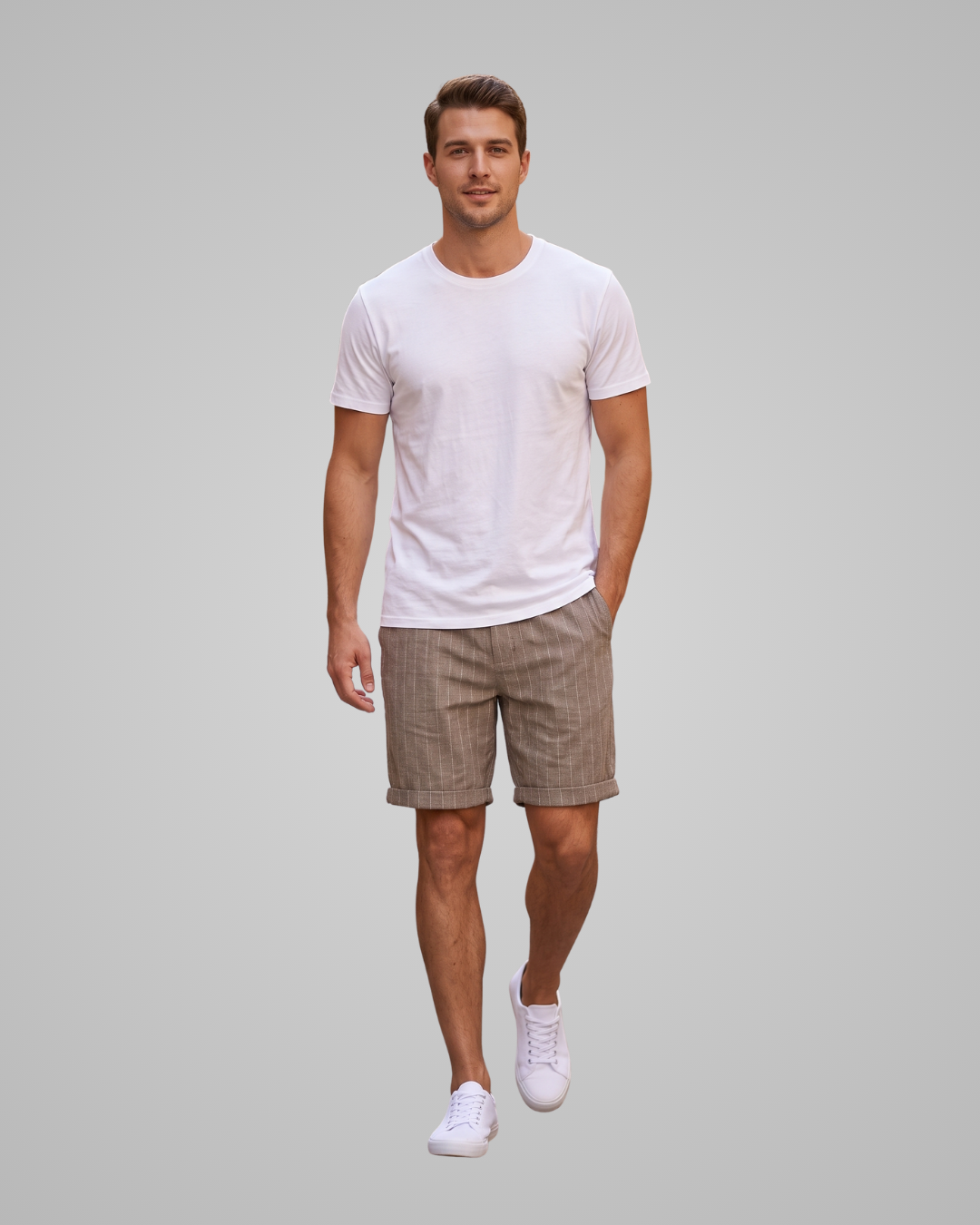 A man modeling a white crew-neck t-shirt and brown plaid shorts against a solid gray background.