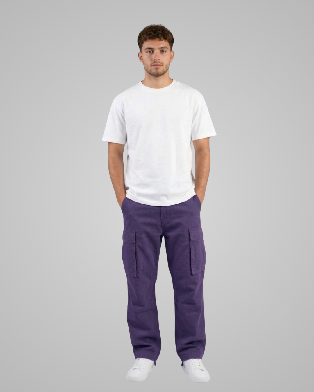 Man wearing a white t-shirt and purple cargo pants on a gray background