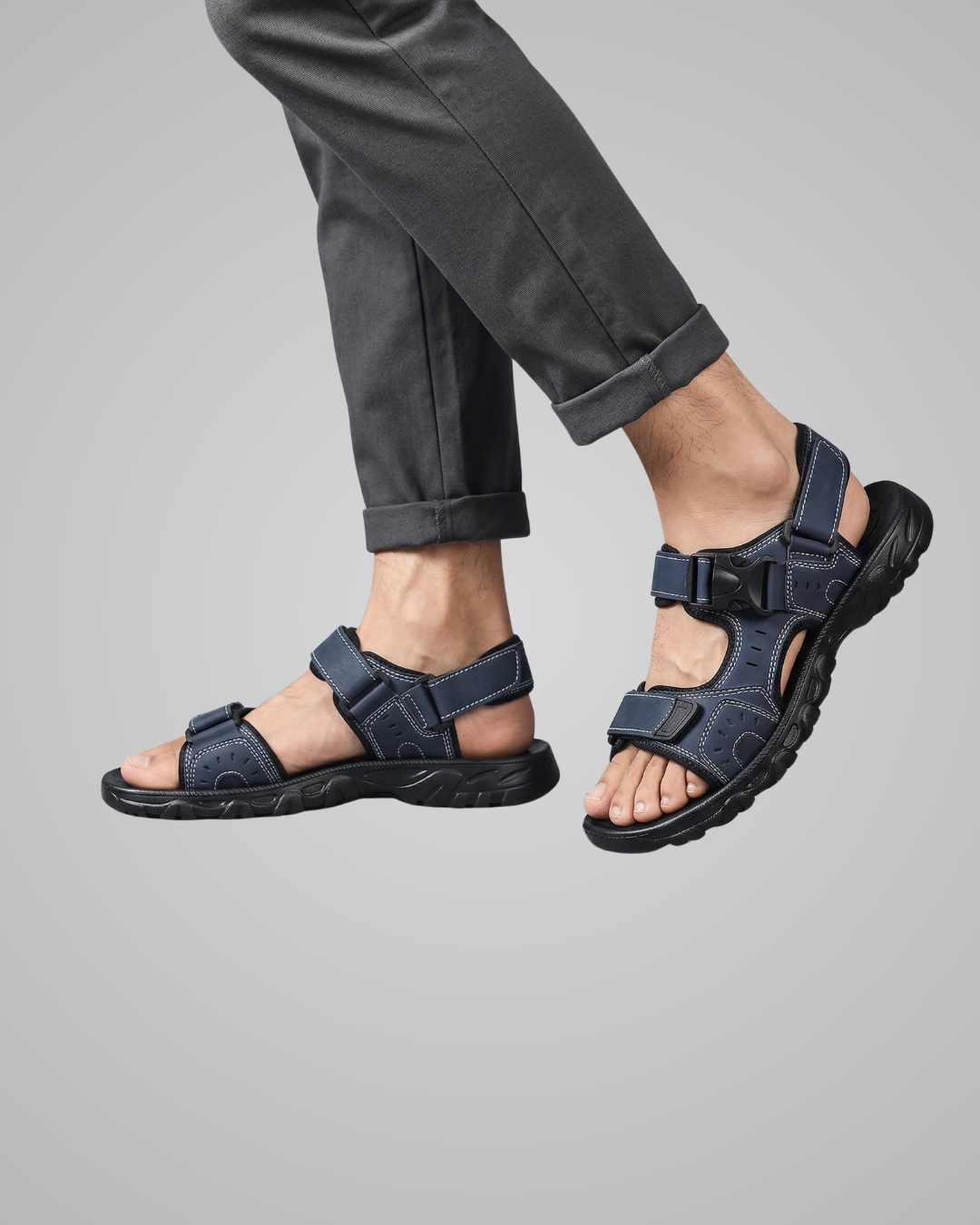 Person wearing dark blue sandals on a gray background