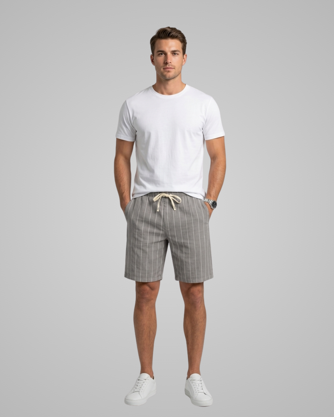 Man wearing a white t-shirt and gray striped shorts on a gray background