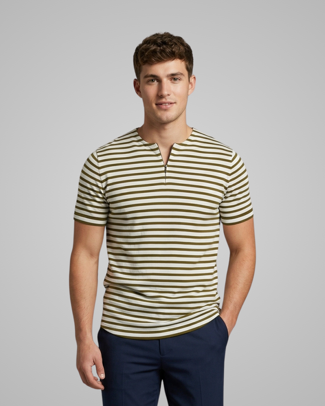 Man wearing a striped shirt and dark pants against a gray background