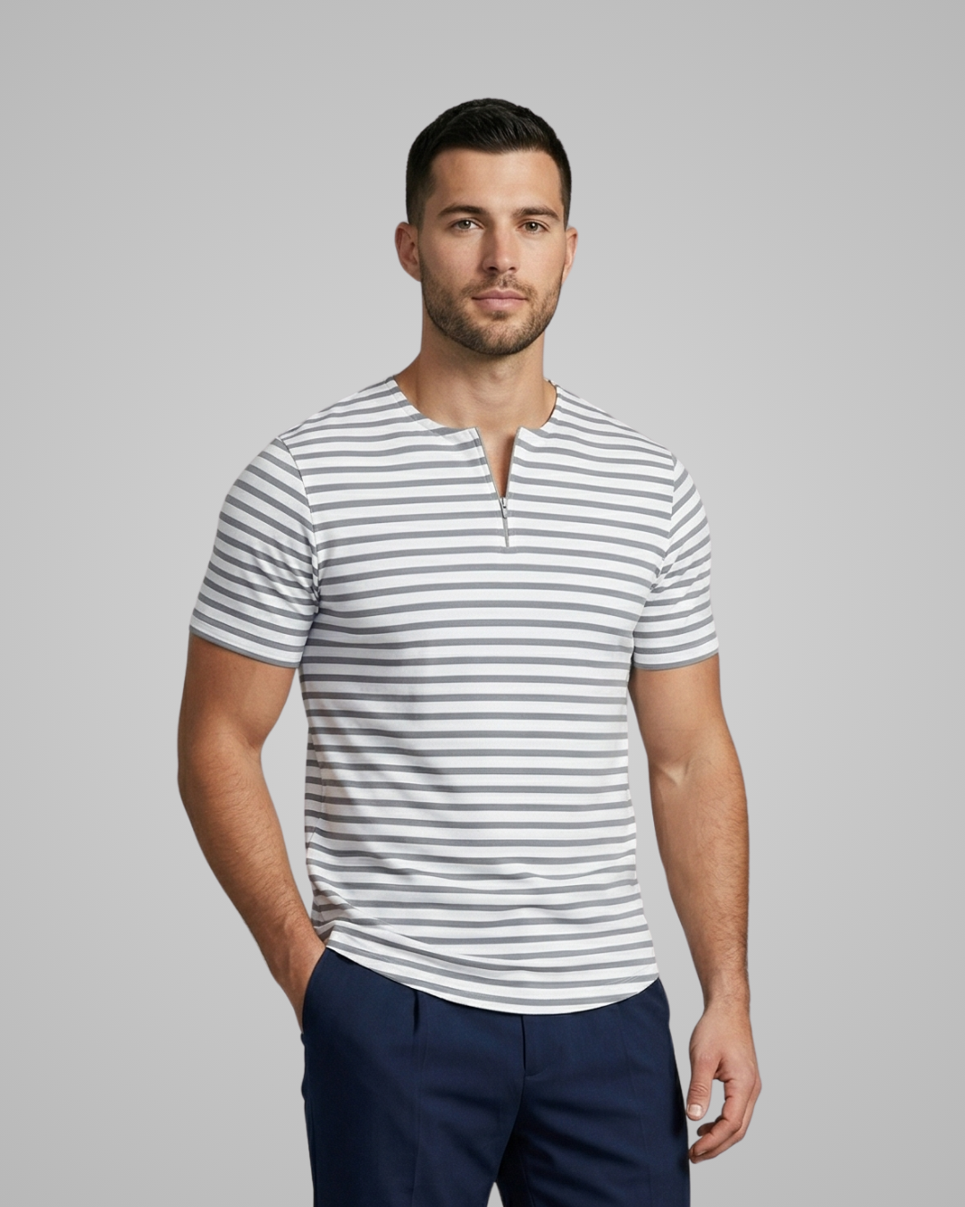Man wearing a striped shirt and navy pants against a gray background