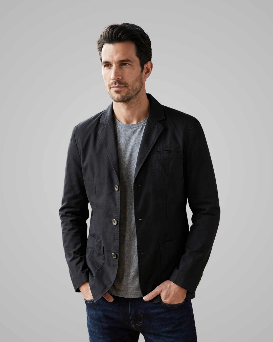 Man wearing a black jacket over a gray shirt on a gray background