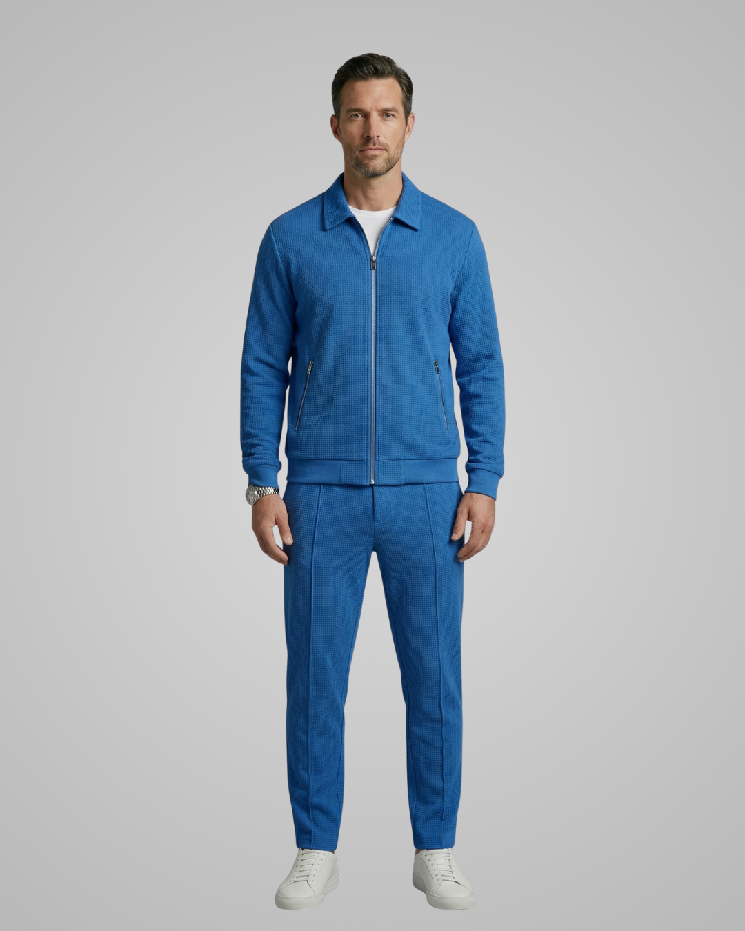 Man wearing a blue tracksuit on a gray background