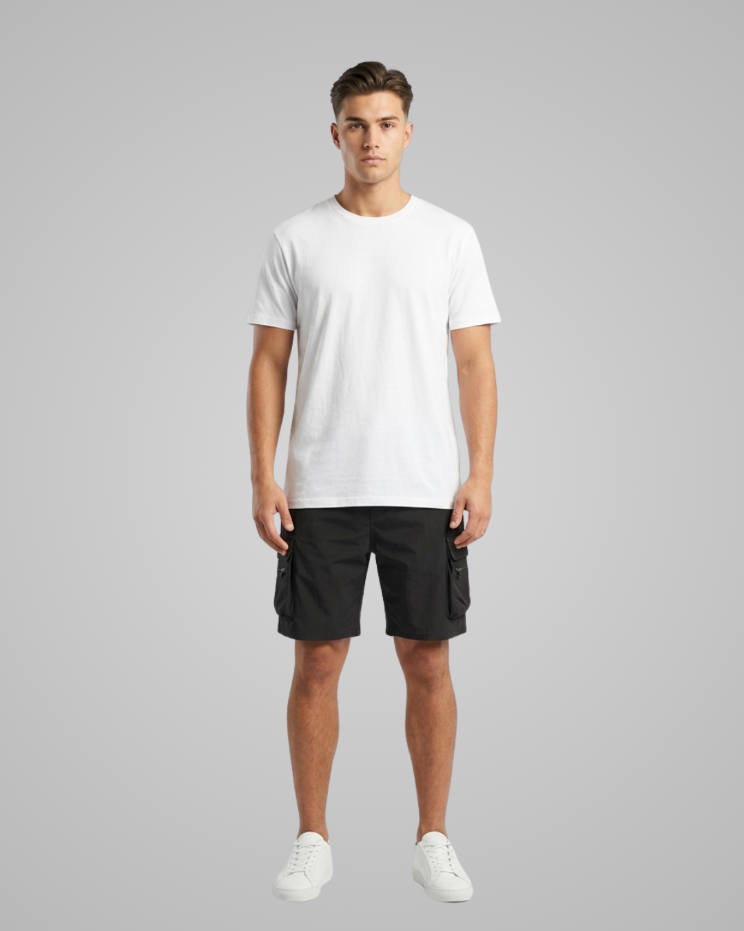 Man wearing a white t-shirt and black cargo shorts on a gray background