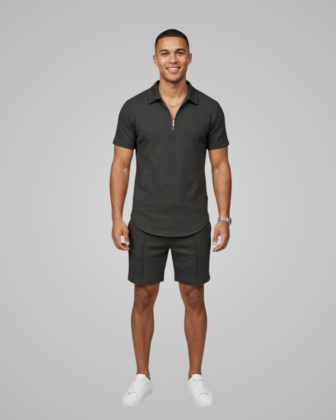 Man wearing a dark gray polo shirt and shorts on a gray background
